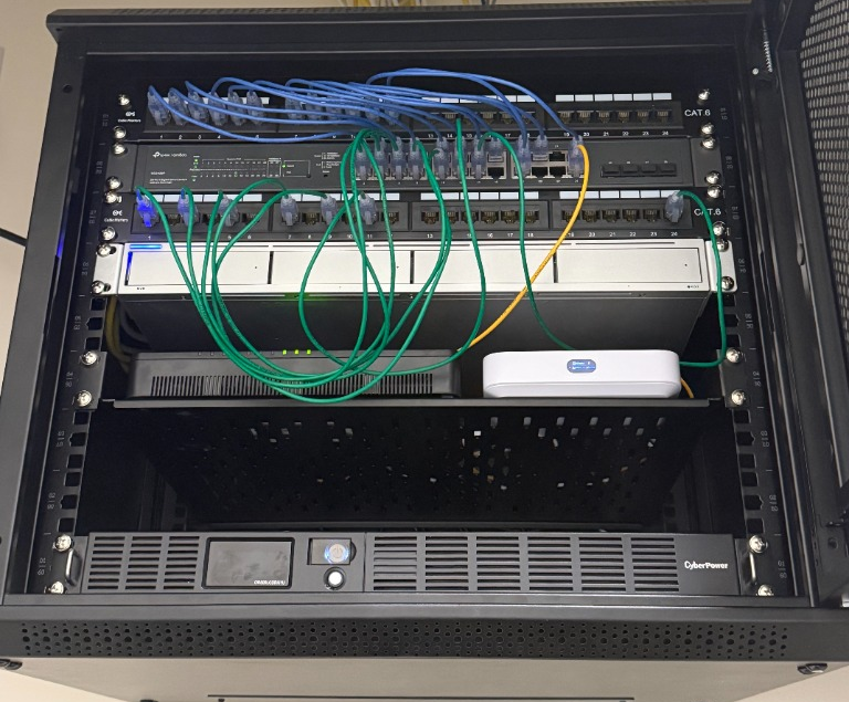 Real open black network rack cabinet showing patch panels and networking equipment configured by Justin Petro